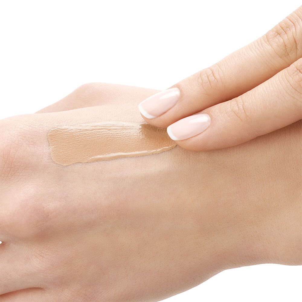 Mano con fondotinta applicato. Fondotinta fluido steso sulla pelle.