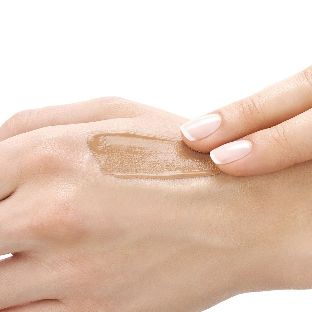 Mano con unghie, applicazione di fondotinta. Tonalità Gold.