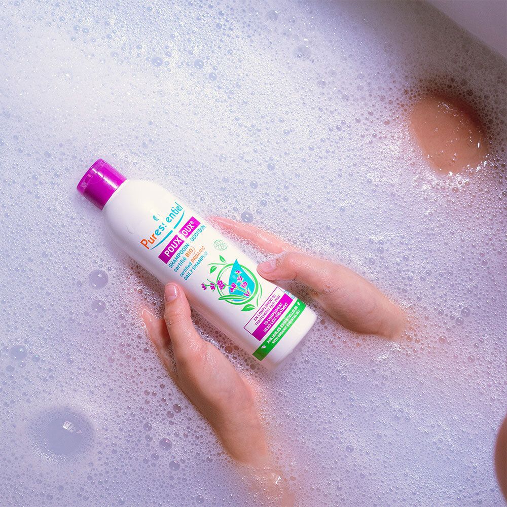 Persona in vasca da bagno con flacone di shampoo. Scritta: Puressentiel Poudoux®.