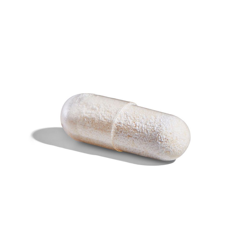 Una capsula oblunga, color crema. Su sfondo bianco.