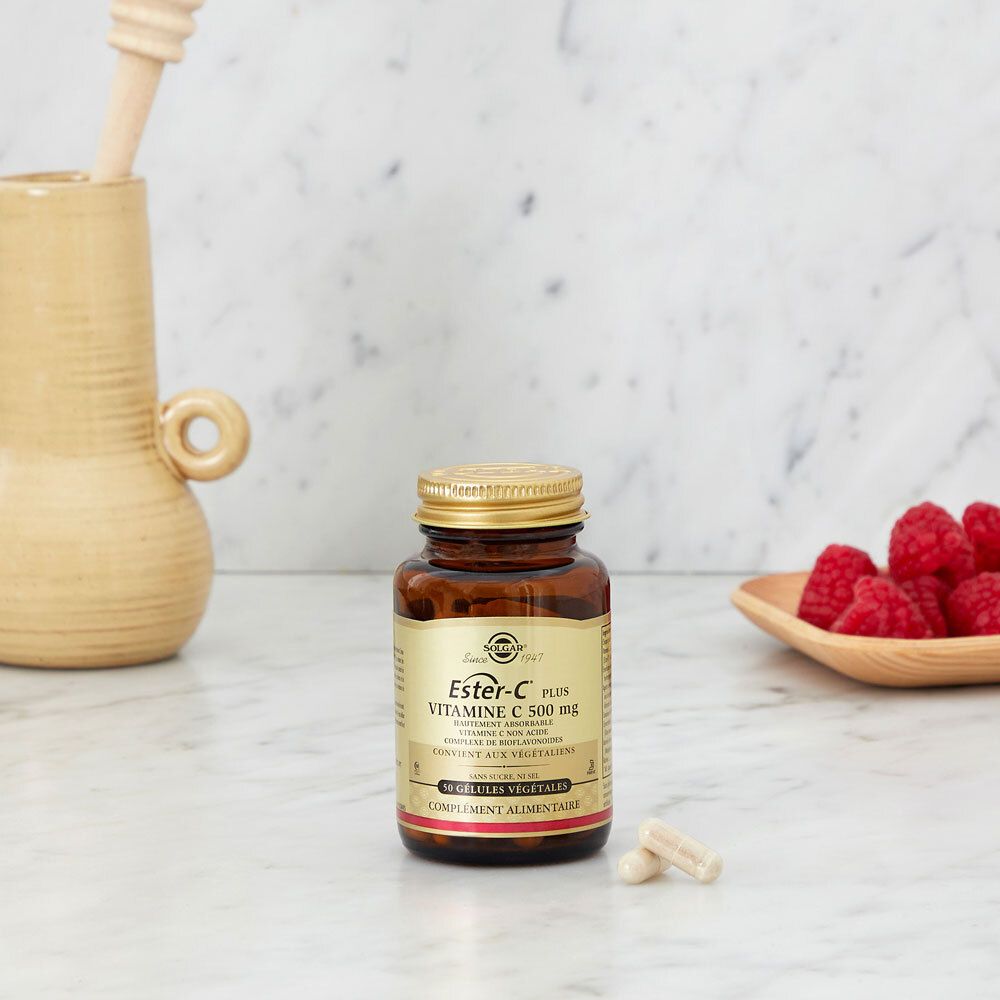 Flacone di capsule di vitamina C su marmo. Lamponi in una ciotola.