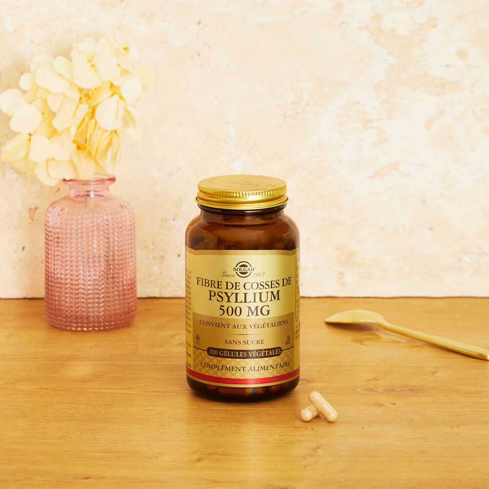 Flacone marrone con capsule e cucchiaio su superficie in legno. Sfondo: vaso con fiori.