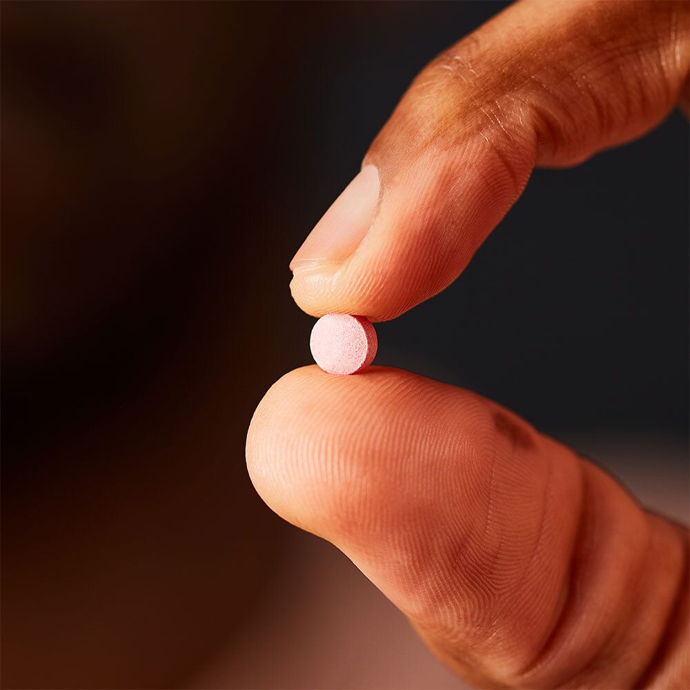 Compressa rosa tenuta tra due dita. Primo piano.