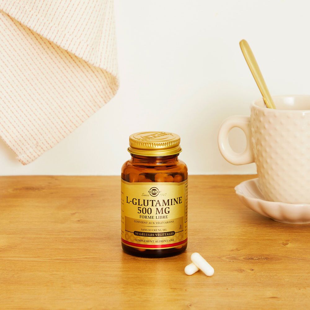 Flacone marrone con capsule su un tavolo. Accanto, una tazza e un cucchiaio. Sfondo chiaro.