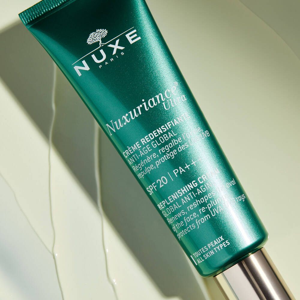 Primo piano di un tubo verde. Scritta: NUXE, Nuxuriance Ultra, Crème-Fluid. Con SPF 20. Testo in francese e inglese.