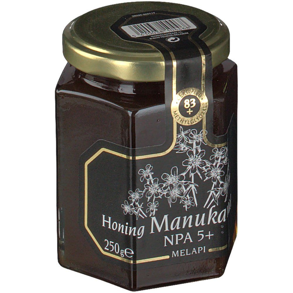Vasetto di miele esagonale con etichetta nera e testo. Coperchio dorato. Scritta 'Honing Manuka NPA 5+' e '250ge'.