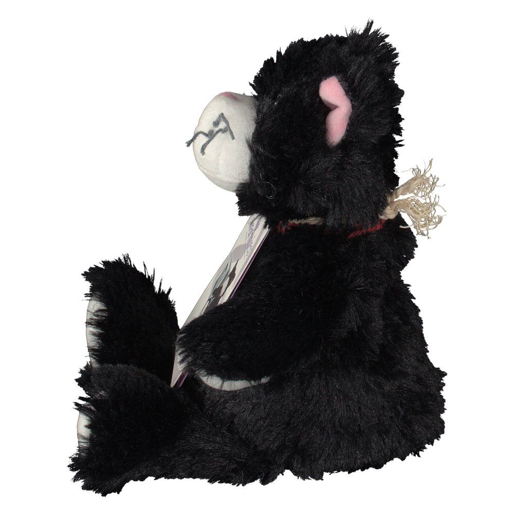 Gatto nero di peluche di profilo, seduto. Visibile: muso bianco, orecchio rosa, etichetta. Etichetta con immagine del prodotto.