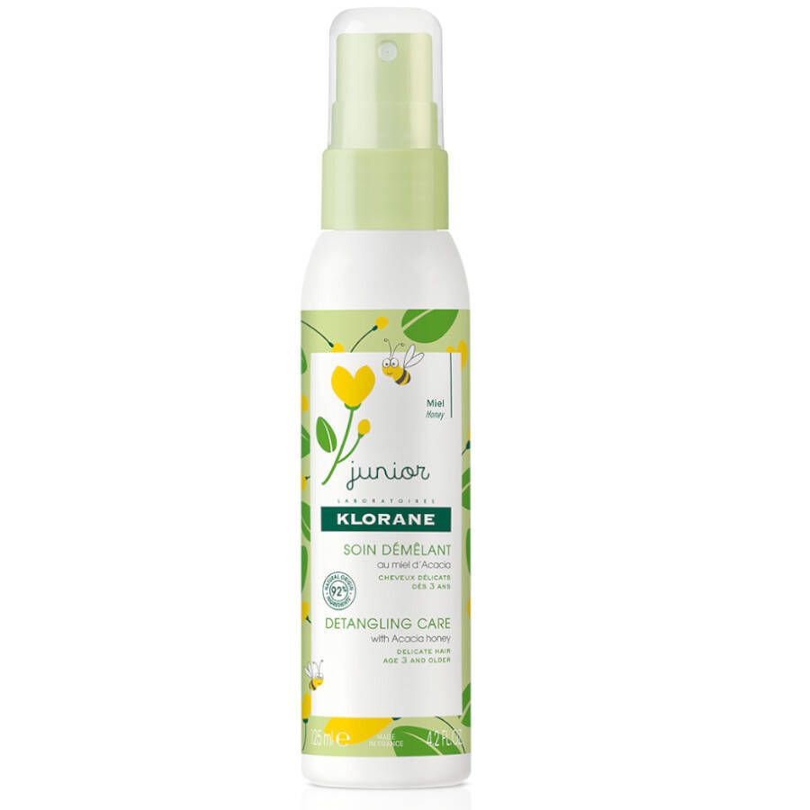 Spray districante Klorane Junior. Flacone bianco con erogatore verde. Design con api e fiori gialli. Scritta: Soin Démêlant.