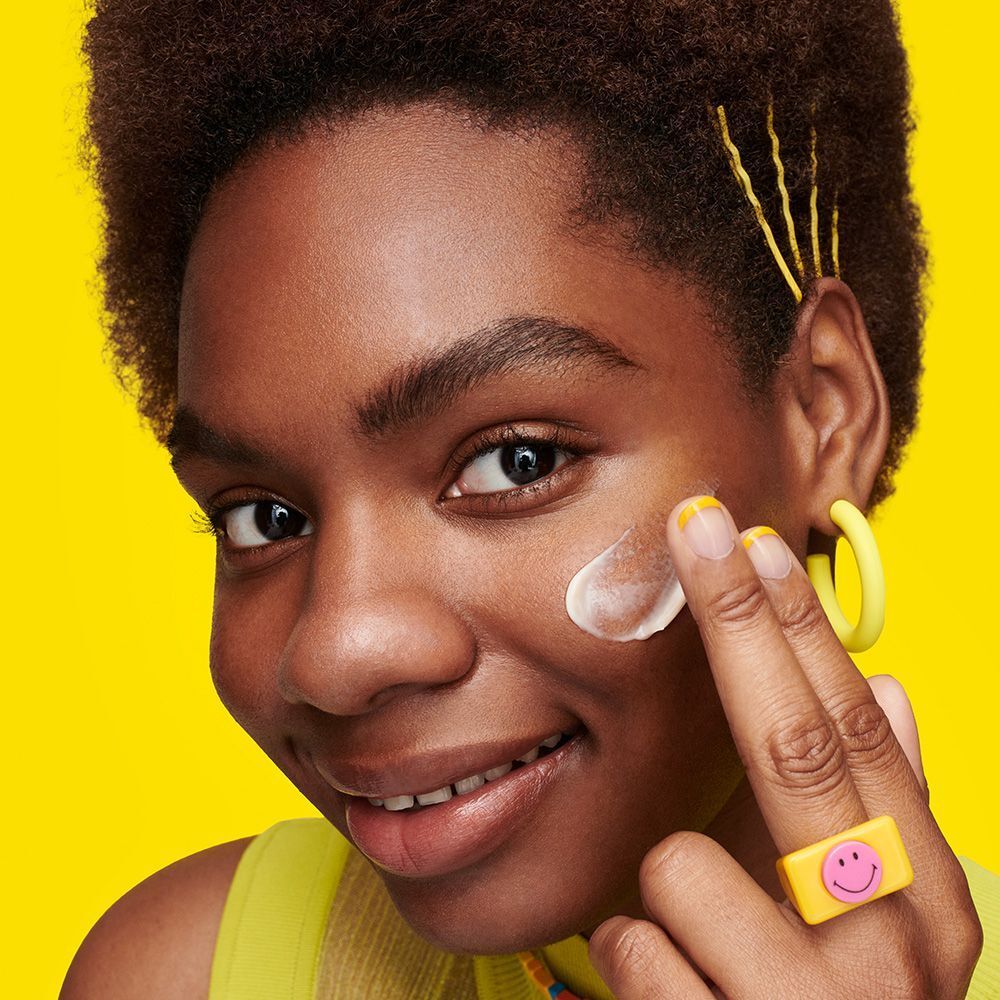 Persona con lozione sul viso. Sfondo giallo. Accessori gialli.
