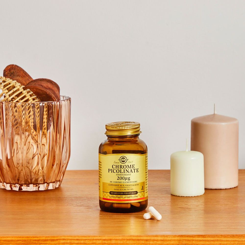 Flacone marrone accanto a candele e decorazioni. Etichetta del prodotto visibile.