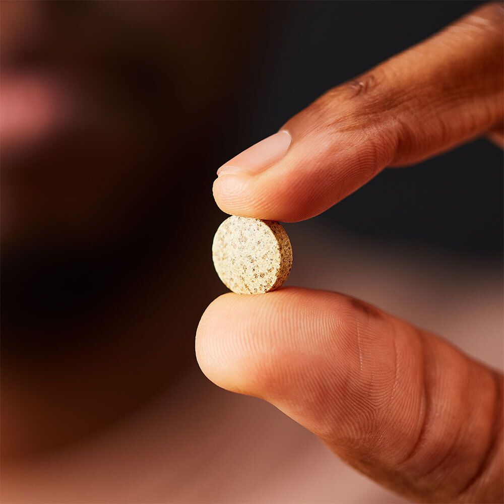 Mano che tiene una compressa. Compressa tra pollice e indice.