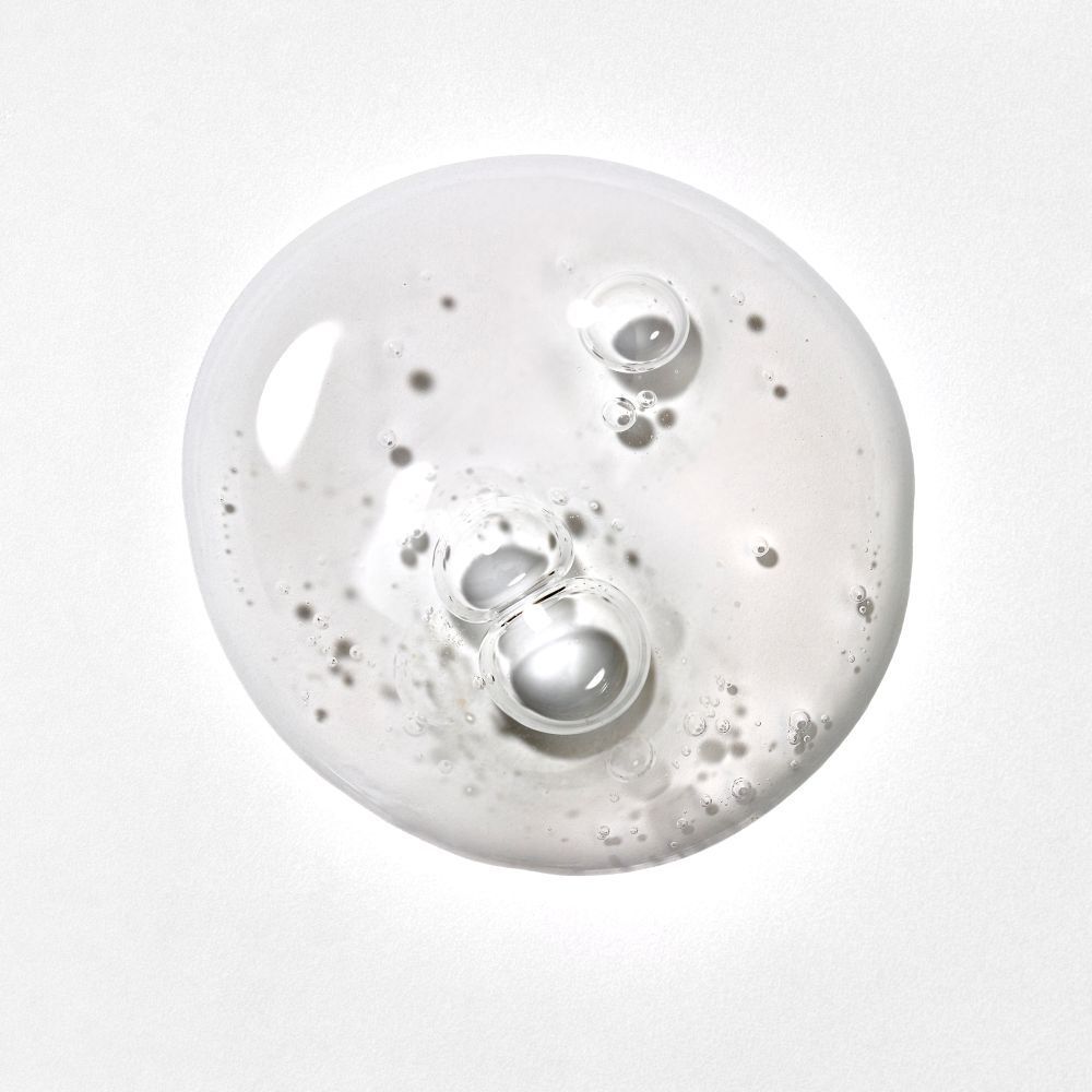 Liquido trasparente con bolle su sfondo bianco. Primo piano.