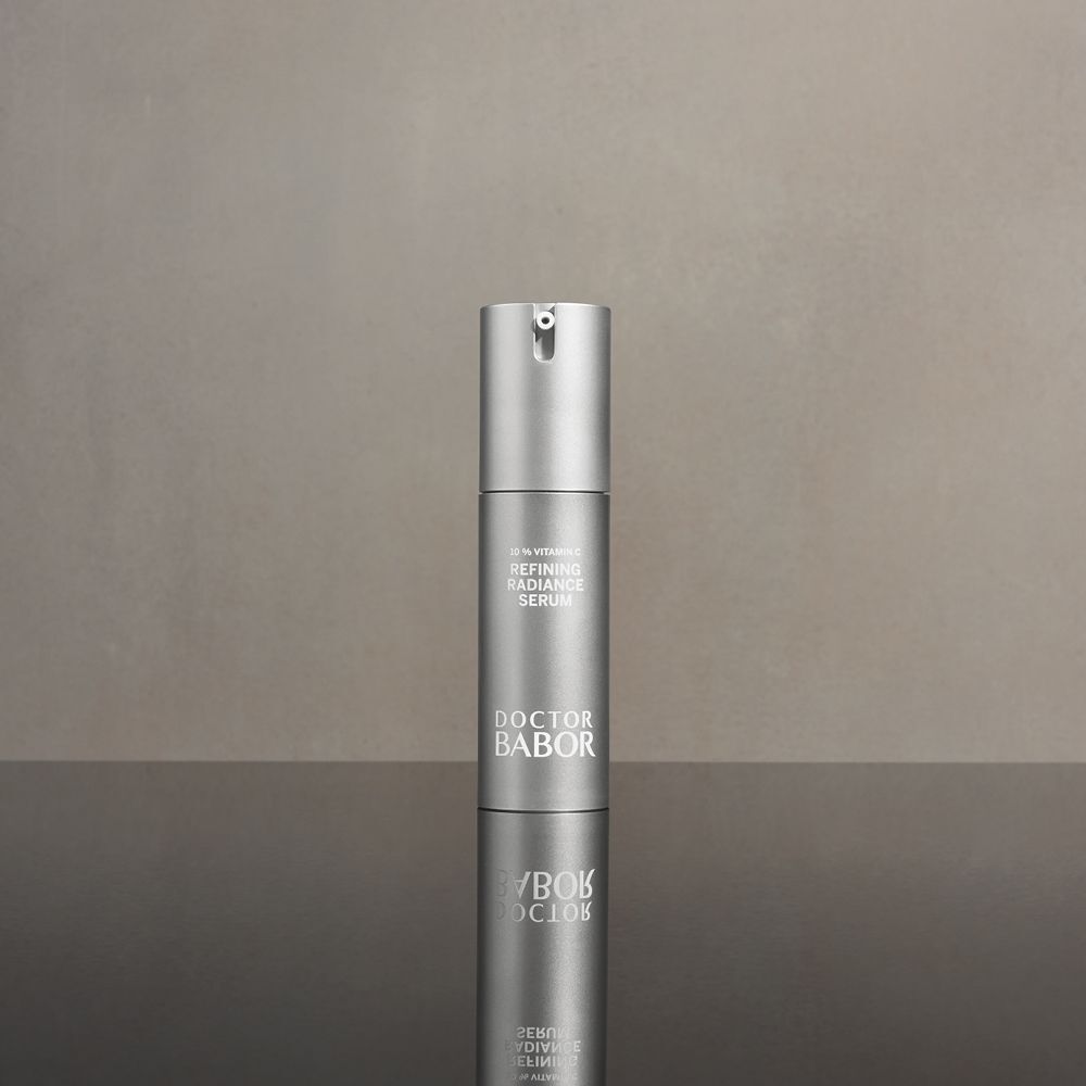 Flacone di siero argentato con dosatore. Scritte: 10% Vitamin C, Refining Radiance Serum, Doctor BABOR. Riflesso.