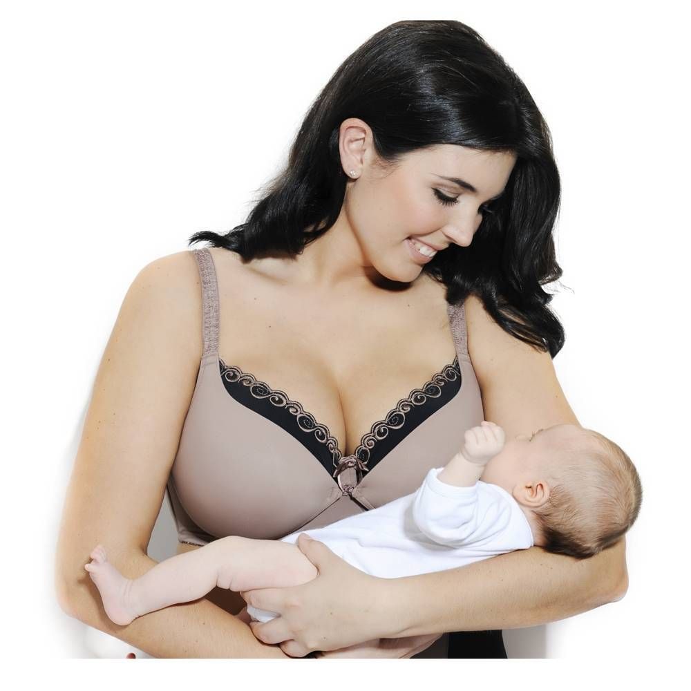 Donna tiene in braccio un bambino, indossa reggiseno allattamento beige con pizzo nero. Guarda in basso.