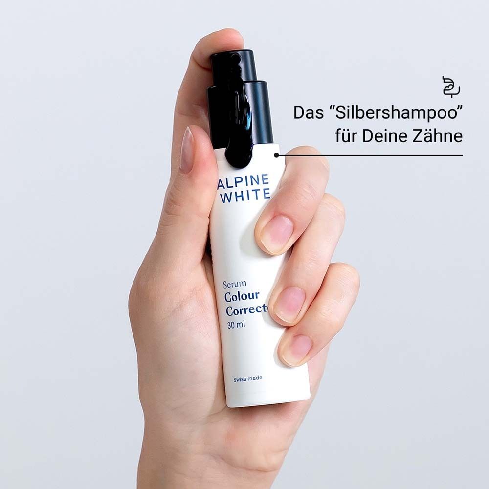 Mano che tiene il flacone di siero. Testo: ALPINE WHITE, Serum Colour Corrector, 30 ml. Tappo nero.
