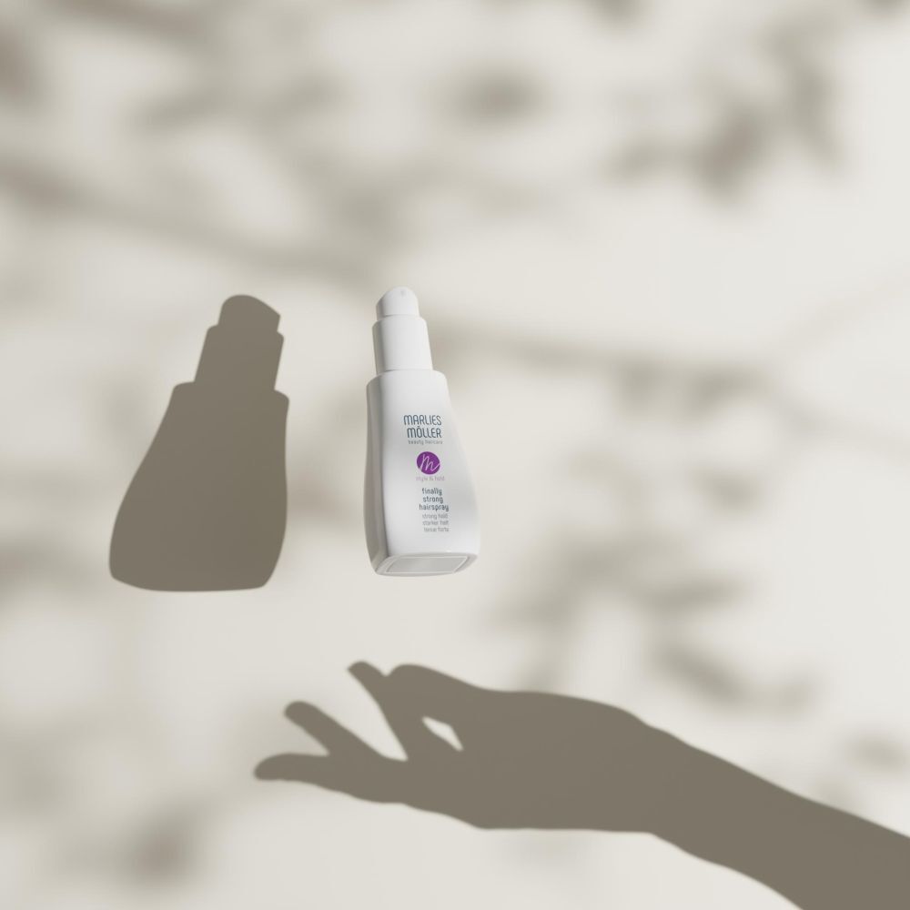 Flacone di lacca fluttuante. Logo Marlies Möller e nome del prodotto. Ombra di una mano.