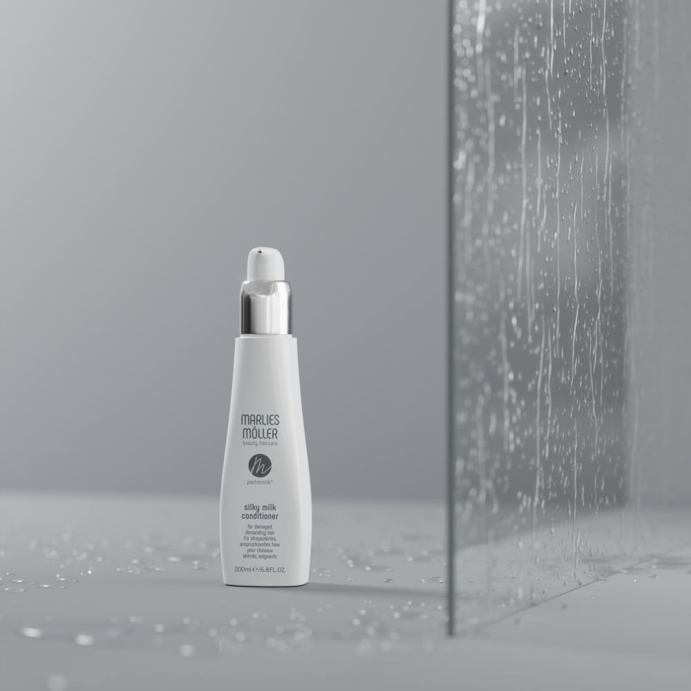 Flacone davanti a una parete di vetro. Flacone: bianco, tappo argentato. Scritta: Marlies Möller, Silky Milk Conditioner.