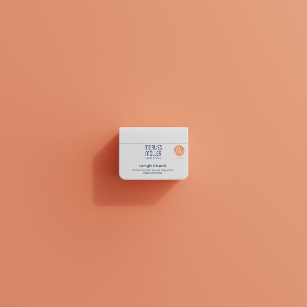 Contenitore bianco Marlies Möller Overnight Hair Mask, su sfondo arancione. Vista dall'alto.