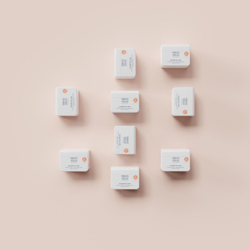 Diversi contenitori bianchi Marlies Möller Overnight Hair Mask, su sfondo rosa. Vista dall'alto.