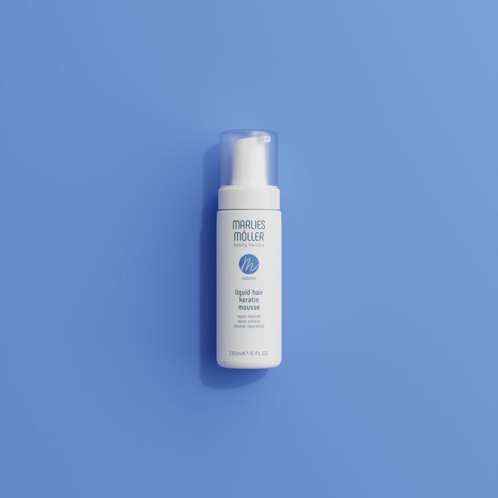 Flacone bianco con erogatore a spruzzo. Scritta: Marlies Möller, beauty haircare, Volume, Liquid Hair Keratin Mousse. Su sfondo blu.