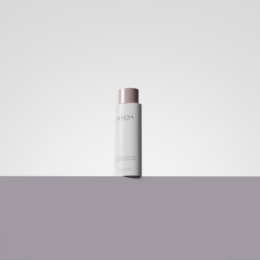 Flacone bianco con tappo rosa. Scritta: Juvena. Il prodotto è posizionato su una superficie grigia.