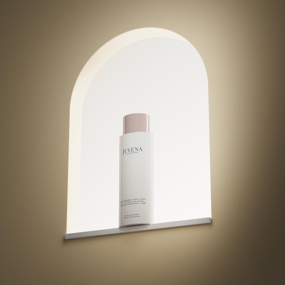 Flacone bianco con tappo rosa. Scritta: Juvena. Prodotto in una nicchia illuminata.