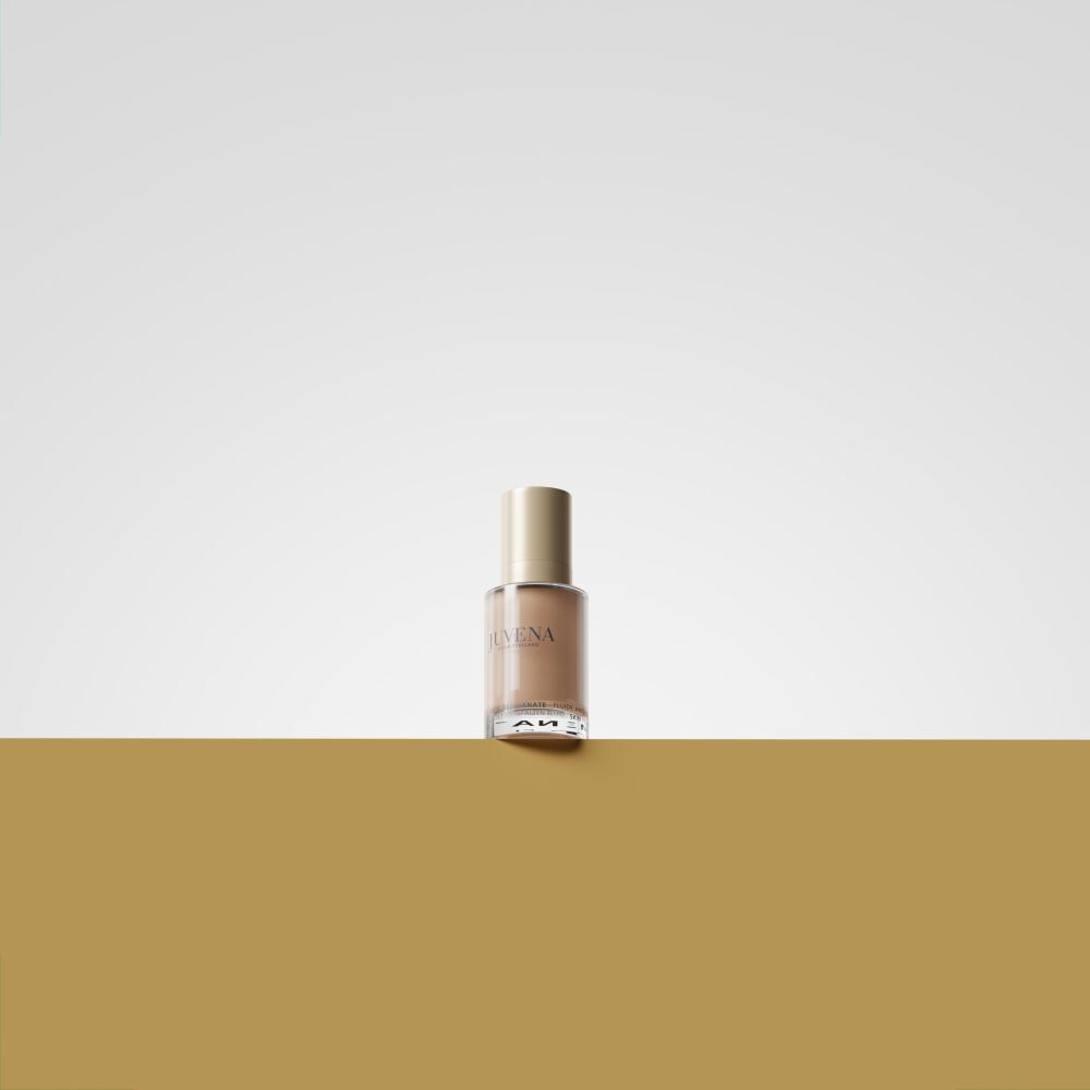 Fluido colorato Juvena of Switzerland. Flacone beige, tappo dorato. Su sfondo chiaro.