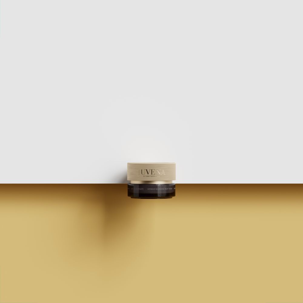 Vaso di crema con coperchio dorato. Scritta: JUVENA. Posizionato su superficie dorata. Sfondo: giallo e bianco.