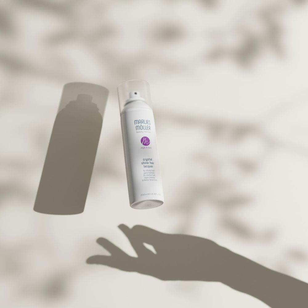 Spray per capelli bianco Marlies Möller. Ombra di una mano. Scritta: Crystal Shine Hair Lacquer.