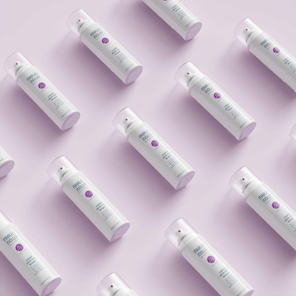 Diversi spray per capelli bianchi Marlies Möller su sfondo rosa. Scritta: Crystal Shine Hair Lacquer.