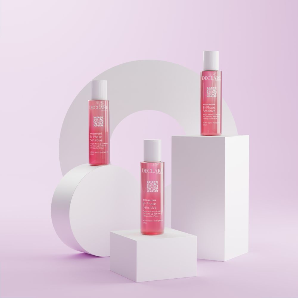 Tre bottiglie. Liquido rosa, tappi bianchi. Testo: DECLARE, EYE CONTOUR, Bi-Phase Sensitive. Su blocchi bianchi.