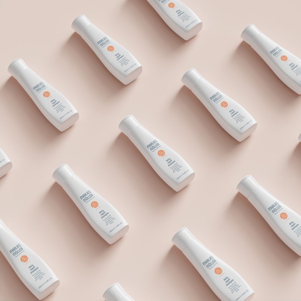 Diversi flaconi di shampoo bianchi su sfondo rosa. Scritta: Marlies Müller, daily repair shampoo. 200ml/6.8FL.OZ.