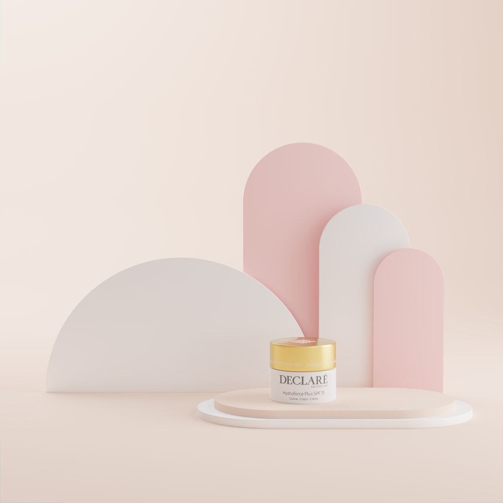 Vaso di crema su piedistallo. Sfondo: forme astratte rosa e bianche. Scritta: DECLARÉ, Hydroforce Plus SPF15.