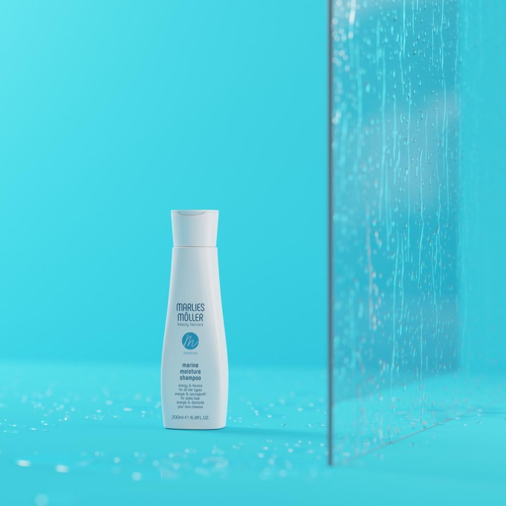 Flacone di shampoo su sfondo blu e vetro. Scritta: Marlies Möller, Marine Moisture Shampoo.