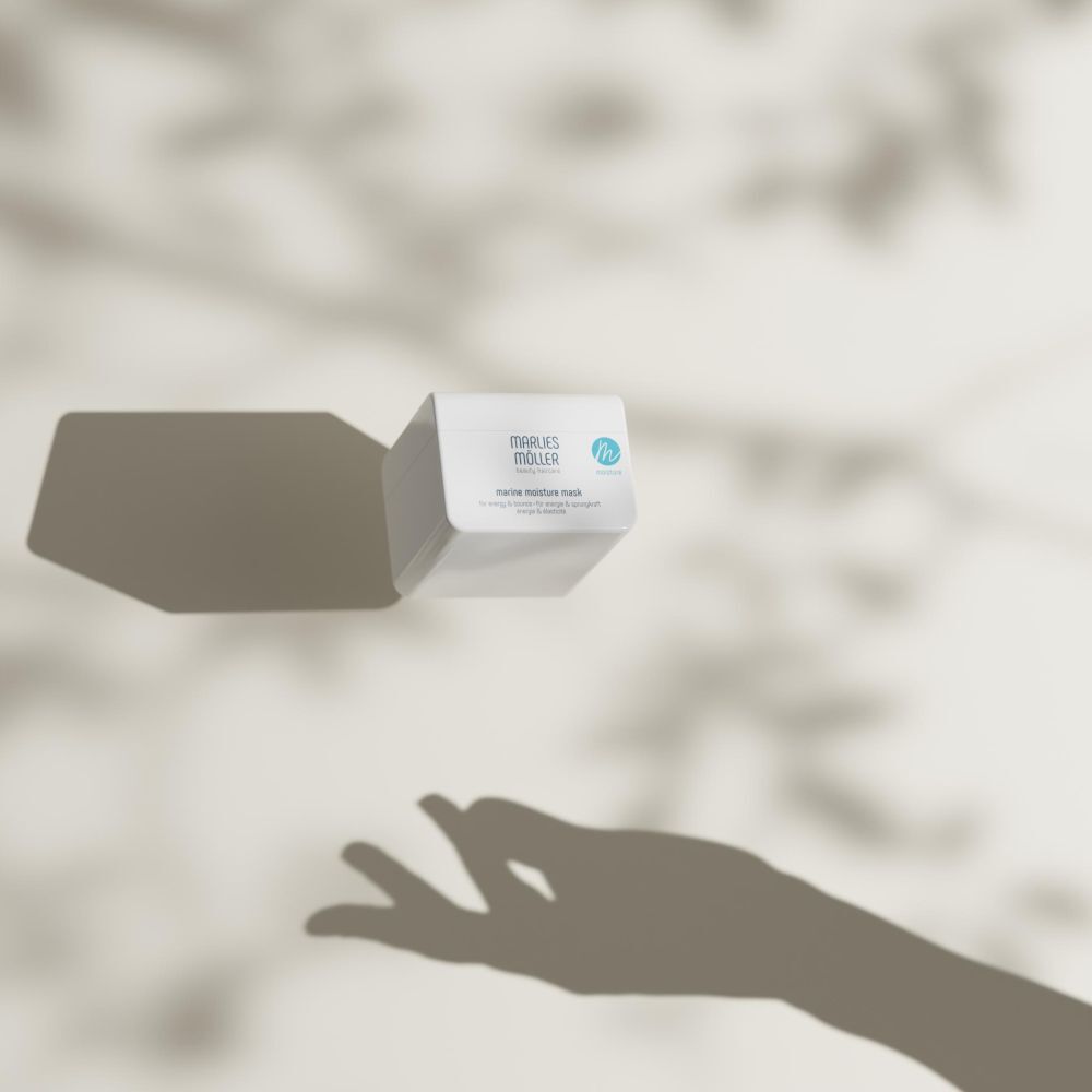 Vaso bianco con ombra. Marlies Möller Marine Moisture Mask. Mano nell'ombra.