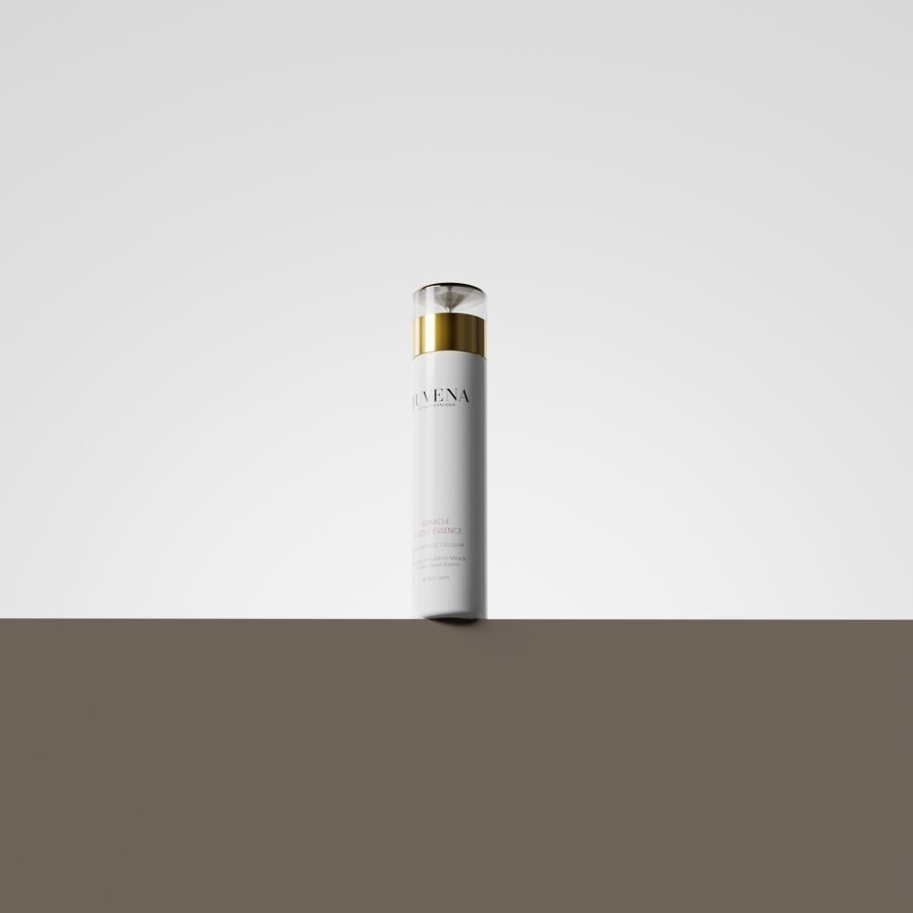Flacone bianco con tappo dorato. Juvena Miracle Boost Essence. Su sfondo marrone.