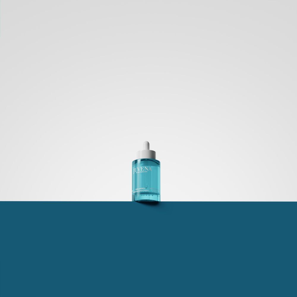 Flacone turchese con tappo bianco e pipetta. Su sfondo bianco e blu.