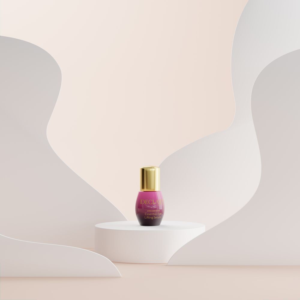 Prodotto su piedistallo. Flacone viola con tappo dorato. Sfondo: forme bianche e sfumatura rosa.