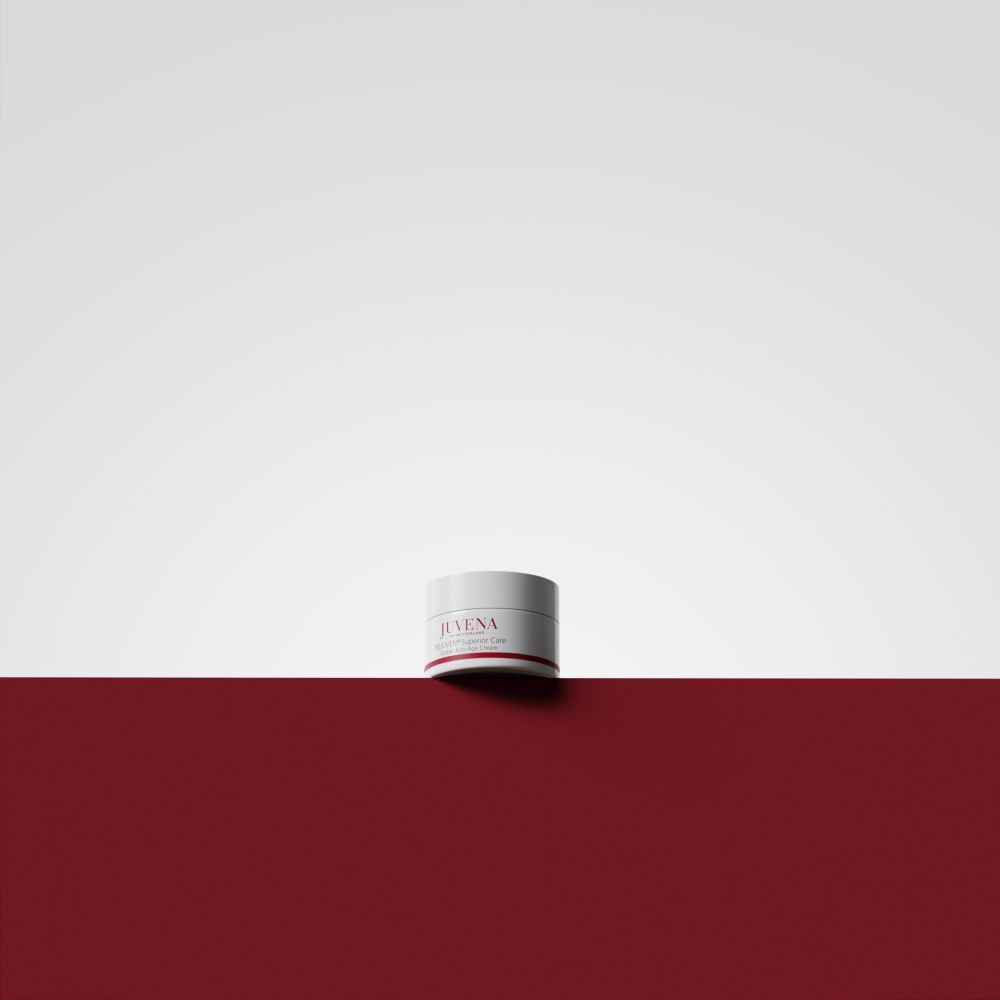 Vasetto di crema su sfondo rosso e bianco. Scritta: JUVENA, REJUVEN® Superior Care. Coperchio bianco, striscia rossa.