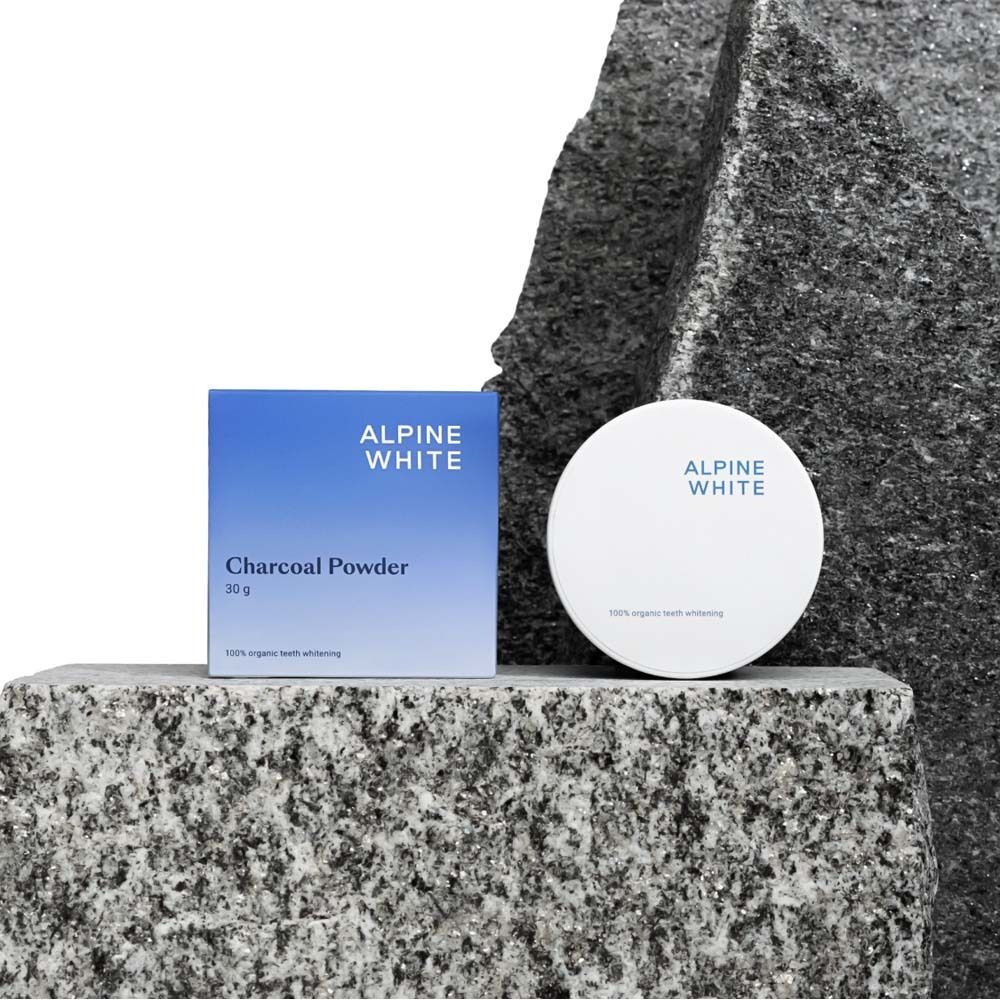 Scatola e barattolo blu e bianchi con "Charcoal Powder". Posizionato su pietra. 30g. Sbiancamento denti organico al 100%.
