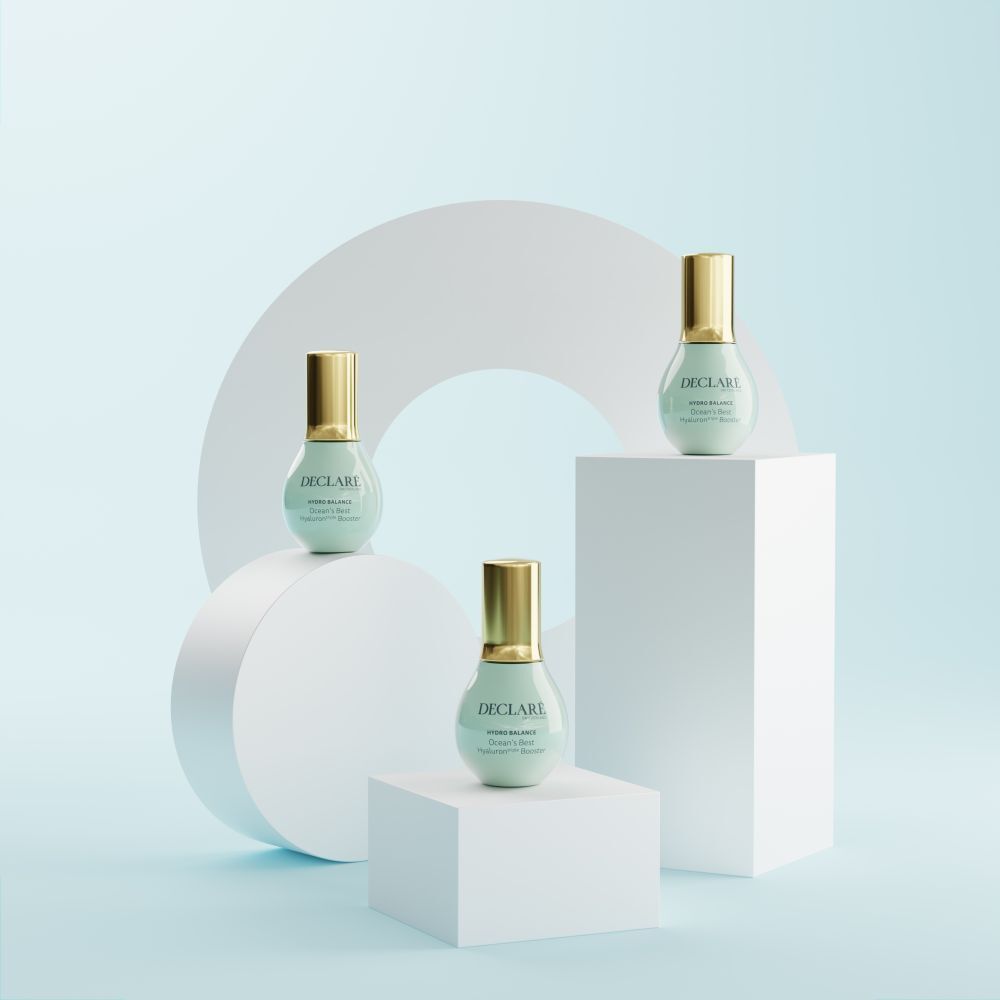 Tre flaconi su piedistalli bianchi. Sfondo: cerchio bianco e sfondo azzurro. Scritta: DECLARÉ, Ocean's Best Hyaluron triple Booster.