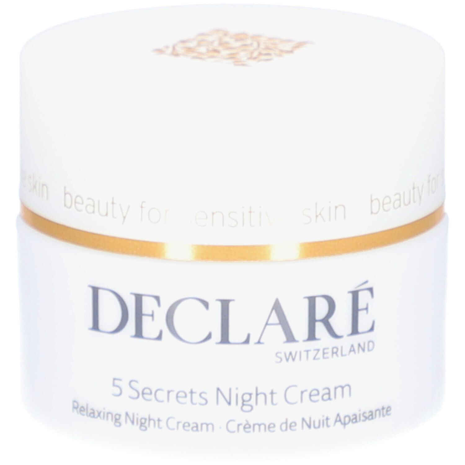 Vasetto bianco con coperchio dorato. Scritta: DECLARÉ, 5 Secrets Night Cream. Testo: Relaxing Night Cream, Crème de Nuit Apaisante.