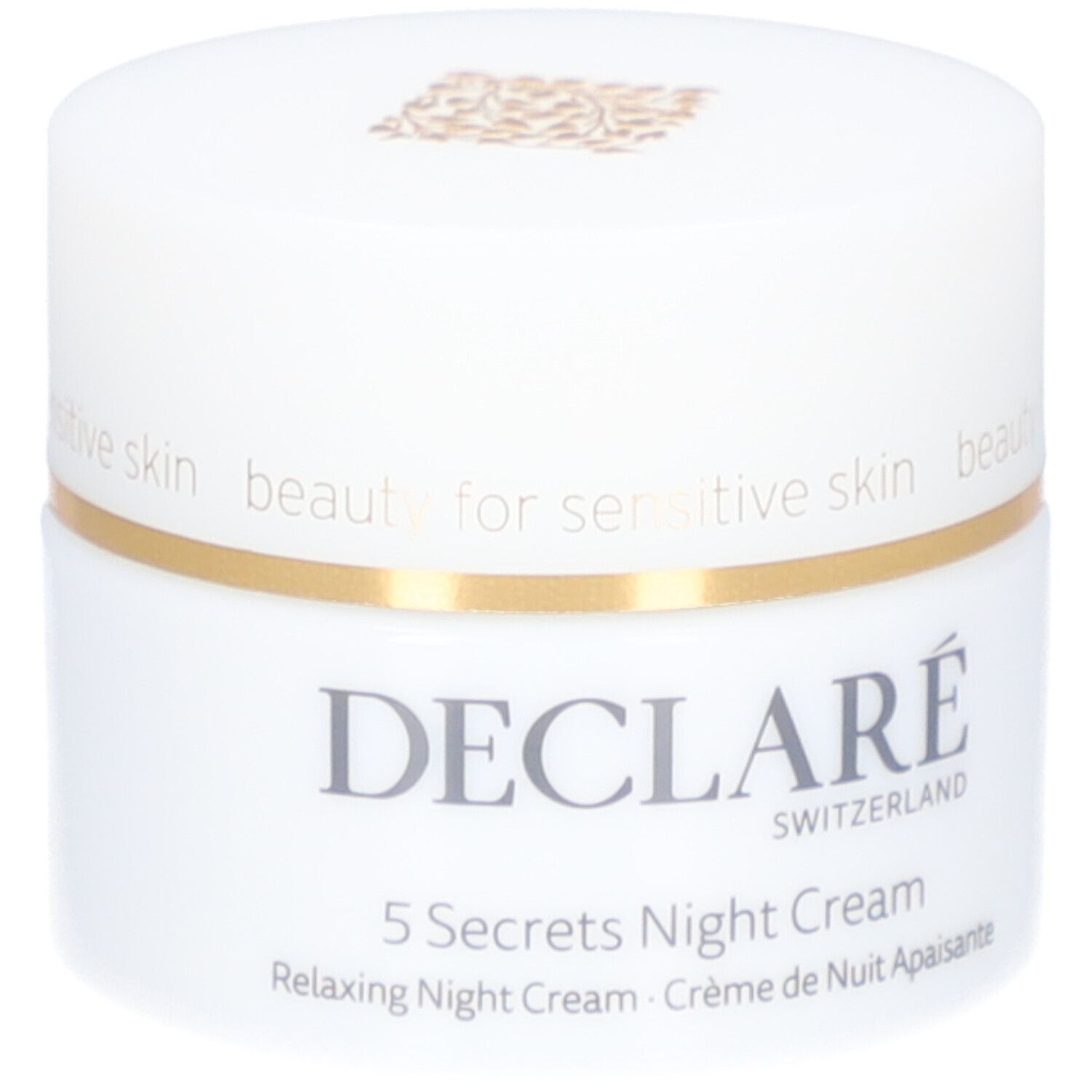 Vasetto bianco con coperchio dorato. Scritta: DECLARÉ, 5 Secrets Night Cream. Testo: Relaxing Night Cream, Crème de Nuit Apaisante.