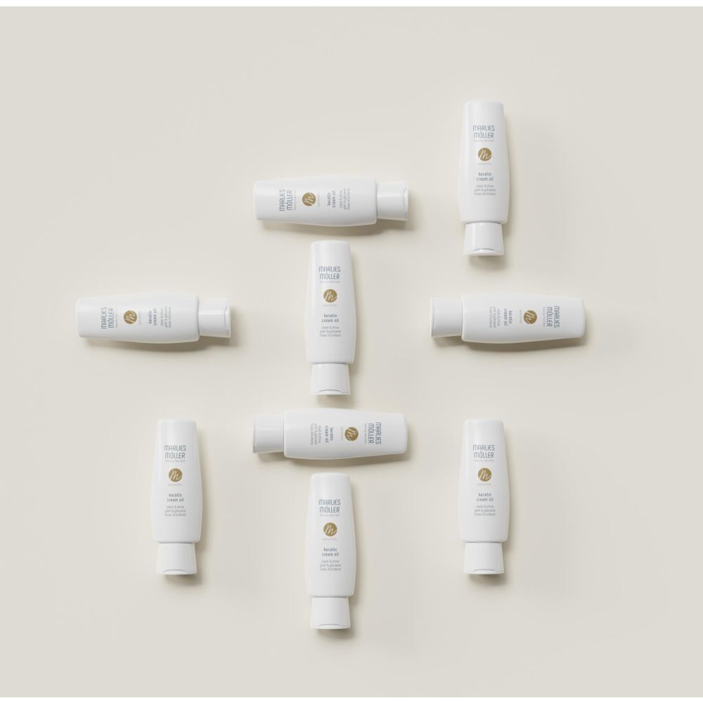 Diversi flaconi bianchi Marlies Möller Keratin Cream Oil. Nome del prodotto, logo e scritta. Liscio e lucente.