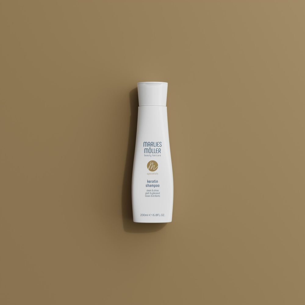 Flacone di shampoo Marlies Möller Keratin su sfondo beige. Flacone con tappo bianco ed etichetta.