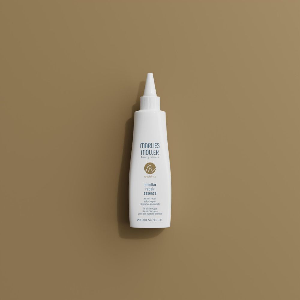 Flacone bianco con beccuccio, Marlies Möller, Lamellar Repair Essence, su sfondo marrone. Vista dall'alto.