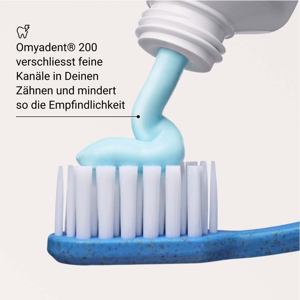 Dentifricio spremuto su uno spazzolino. Testo: Omyadent® 200 chiude i canali sottili dei denti.