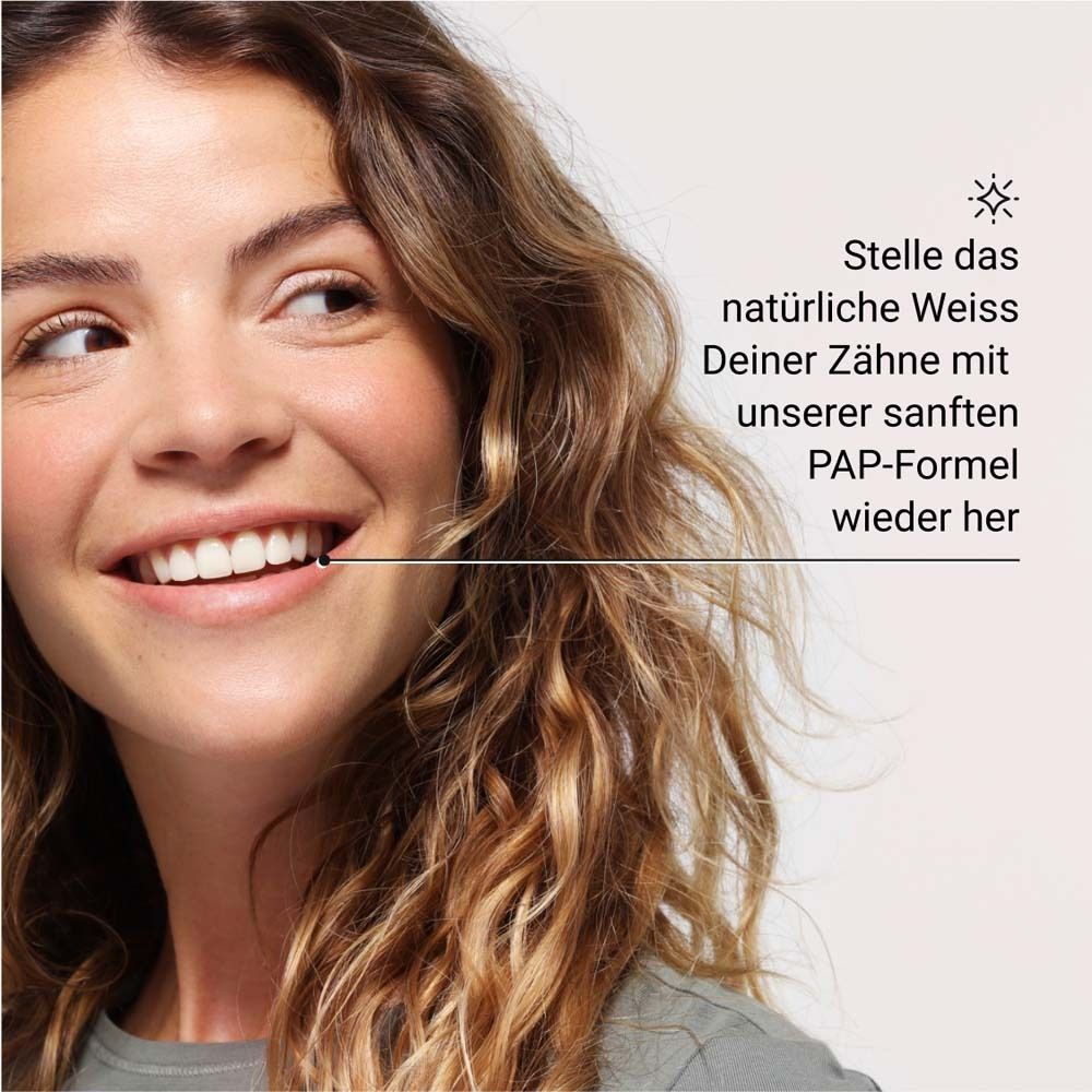 Donna sorridente. Testo: Ripristina il bianco naturale dei tuoi denti con la nostra delicata formula PAP.