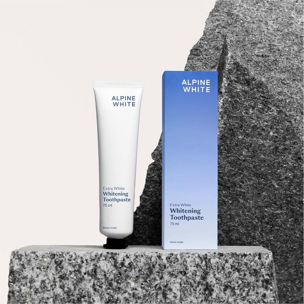 Tubo e scatola di dentifricio su una pietra. Scritta: ALPINE WHITE, Extra White Whitening Toothpaste.