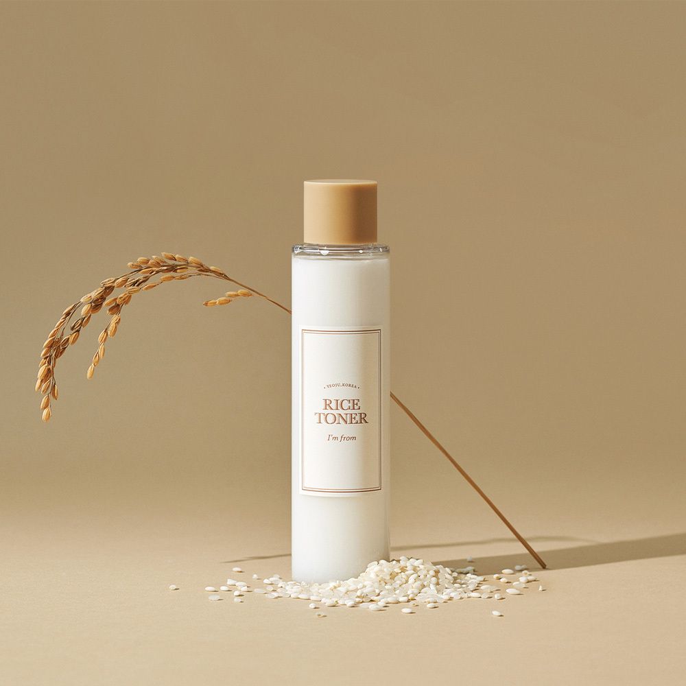 Flacone bianco con tappo beige-dorato, etichetta 'RICE TONER'.